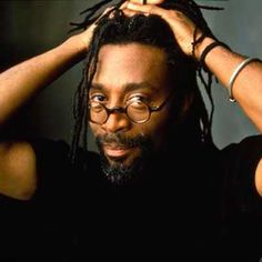 a man with glasses and dreadlocks is holding his hair in front of his head