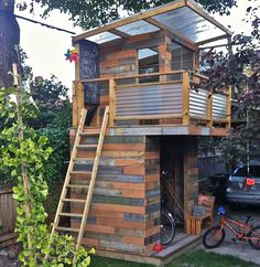 a small wooden structure with stairs to the top and second story above it, next to a bike