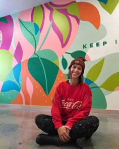 a woman sitting on the floor in front of a colorful wall