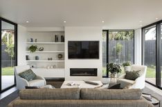 a living room filled with furniture and a flat screen tv mounted on a wall above a fire place