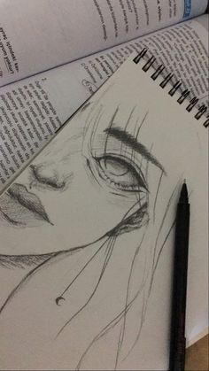 an open book with a drawing of a woman's face next to a pencil