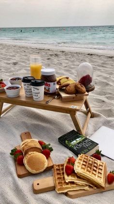 some waffles and strawberries are on the beach