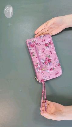 two hands holding a pink flowered purse