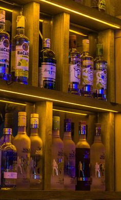 bottles of alcohol are lined up on the shelf in front of each other, all lit up with blue lights