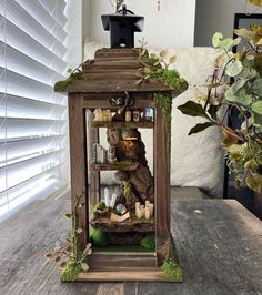 a small wooden lantern with moss growing on it's sides and candles in the top