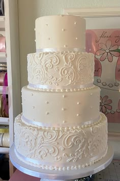 a three tiered white wedding cake sitting on top of a table