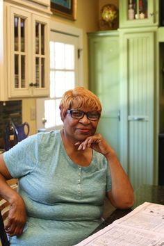 a woman sitting at a kitchen table in front of a paper on top of a counter