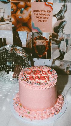 a pink cake with sprinkles on it sitting next to disco balls and posters