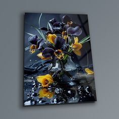 a vase filled with purple and yellow flowers on top of a black table cloth covered in water