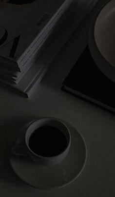 a cup of coffee sitting on top of a table next to a book and a bowl