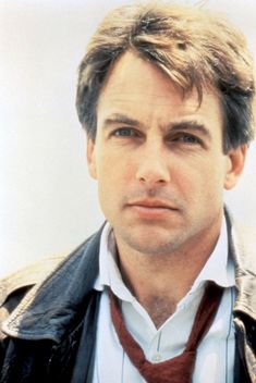 a man in a leather jacket and tie looking at the camera with a serious look on his face