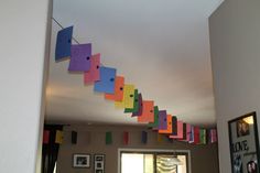 colorful paper streamers hanging from the ceiling in a room with pictures on the wall