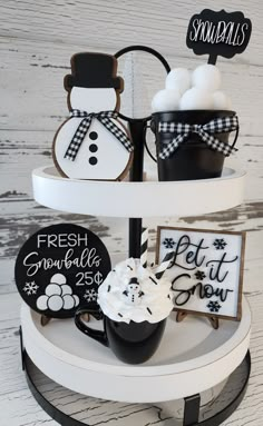 three tiered tray with cupcakes, cookies and decorations on it in black and white