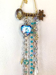 a key hanging from a chain with charms and beads on it's side, attached to a wall