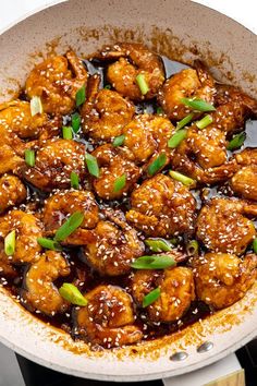 chicken with sesame seeds and green onions in a skillet on top of the stove