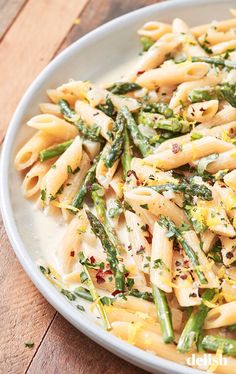 pasta with asparagus and parsley in a white bowl on a wooden table