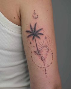 a woman's arm with a palm tree and crescent moon tattoo on the left shoulder