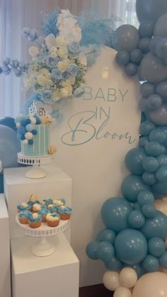 blue and white baby shower party with balloons, cupcakes and cake on display