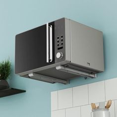 a microwave mounted on the wall above a potted plant next to a stove top oven