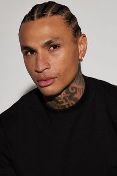 a young man with tattoos on his neck and chest looks at the camera while wearing a black shirt