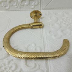 a gold colored metal hook on a white wall