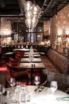 an empty restaurant with long tables and red upholstered booths, lights hanging from the ceiling