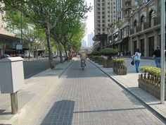 people walking and riding bicycles on a city street with tall buildings in the back ground