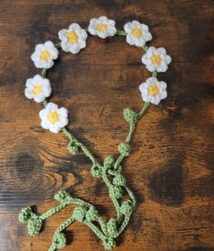 a crocheted bracelet with white and yellow flowers attached to it on a wooden table