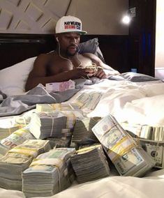 a man laying in bed with stacks of money