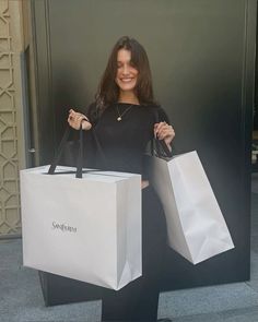 a woman holding two shopping bags and smiling