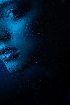 a woman's face is shown through the raindrops on a dark background