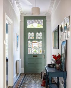 a green front door with stained glass windows and an ornate tile floor in the hallway