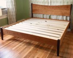 a wooden bed frame sitting on top of a hard wood floor next to a window