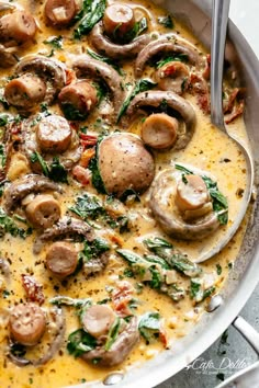 a pan filled with mushrooms and spinach on top of a table next to a fork