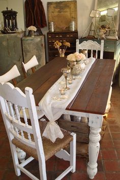 a wooden table with white chairs and flowers on it