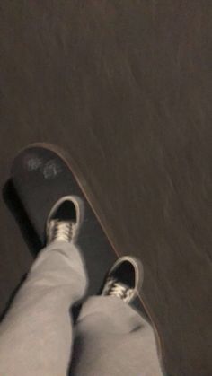 a person standing on top of a skateboard next to the ground with their feet up