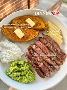 a white plate topped with steak, potatoes and other food items next to a brick wall