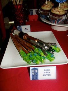 a plate with some food on it and cupcakes in the background at a doctor who party