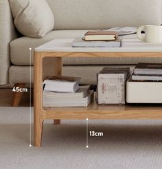 a coffee table with books and magazines on it, next to a couch in the living room