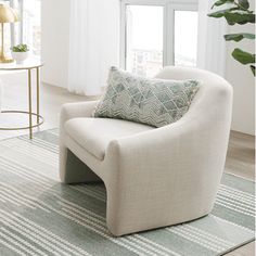 a living room with a chair and rug in front of a large window that looks out onto the city