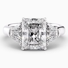 a three stone diamond ring with two princess cut diamonds in the center and side stones on each