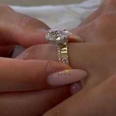 a woman's hand holding an engagement ring with two diamonds on it and the other hand