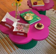 two pink tables with donuts on them and a vase full of sunflowers