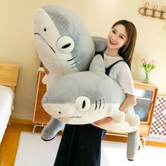 a woman holding two stuffed sharks in her hands