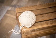 a white knitted hat sitting on top of a wooden bench next to a string