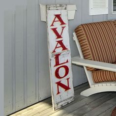 a wooden sign sitting on the side of a building next to a chair and rug