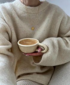 an older woman holding a cup of coffee in her right hand while sitting on a couch