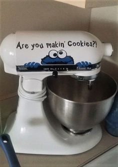 a white mixer sitting on top of a counter next to a blue ball and spatula