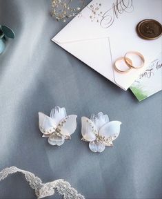 two wedding rings are sitting on a table next to some flowers and an envelope with a card