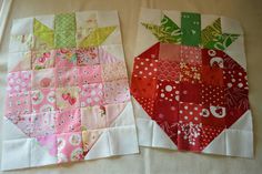 two quilted apples sitting side by side on a white tablecloth with pink and green designs